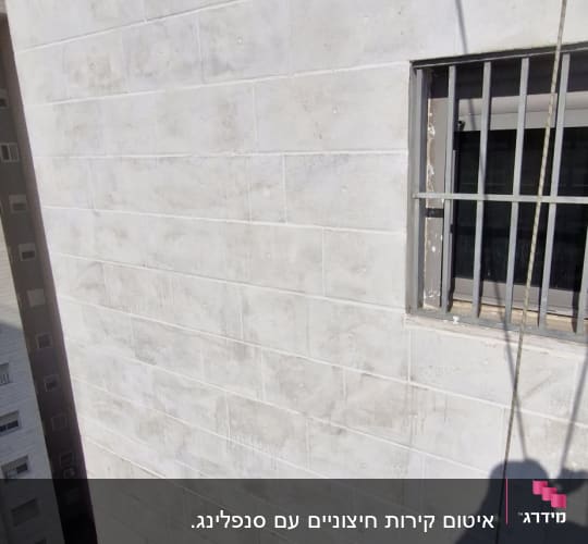 קיר בניין עם חלון וסורג, צל אדם על הקיר